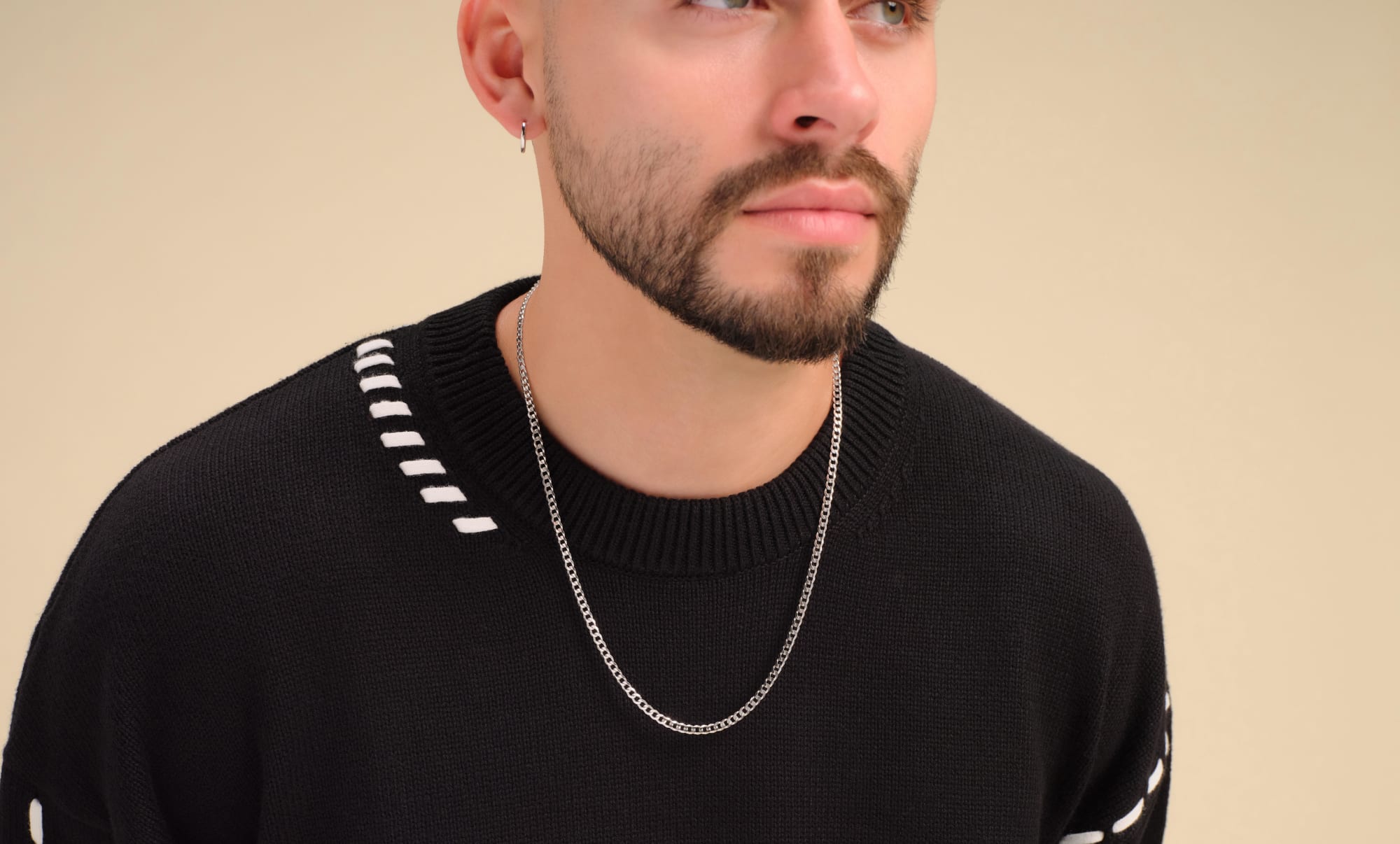 A male model wearing the JAXXON 3mm Silver Curb Chain styled with a black crewneck sweater with white stitch detailing.