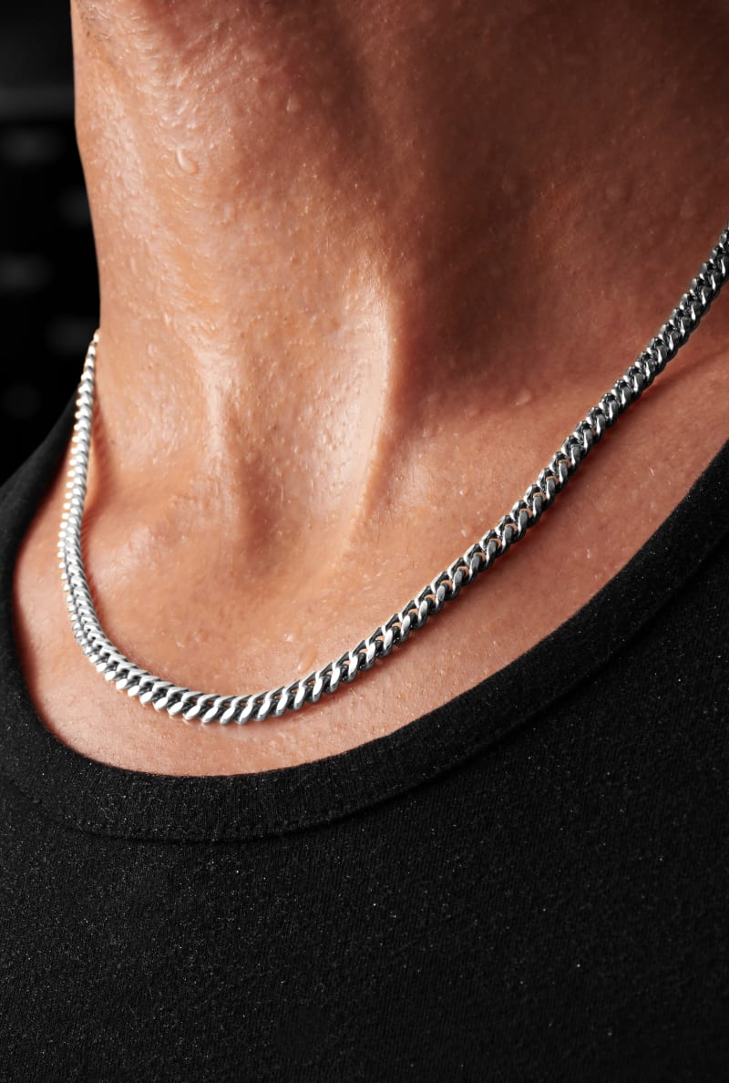 A zoomed in view of JAXXON's Silver 5mm Cuban Link Chain around a man's neck.