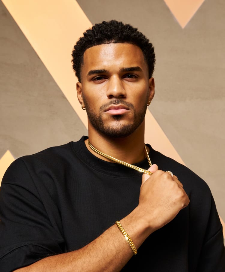 A man wearing a JAXXON gold Cuban link chain at a Kay Jewelers store