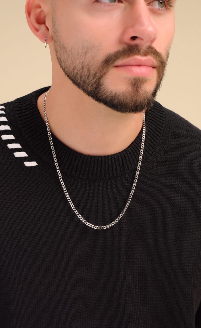 A male model wearing the JAXXON 3mm Silver Curb Chain styled with a black crewneck sweater with white stitch detailing.