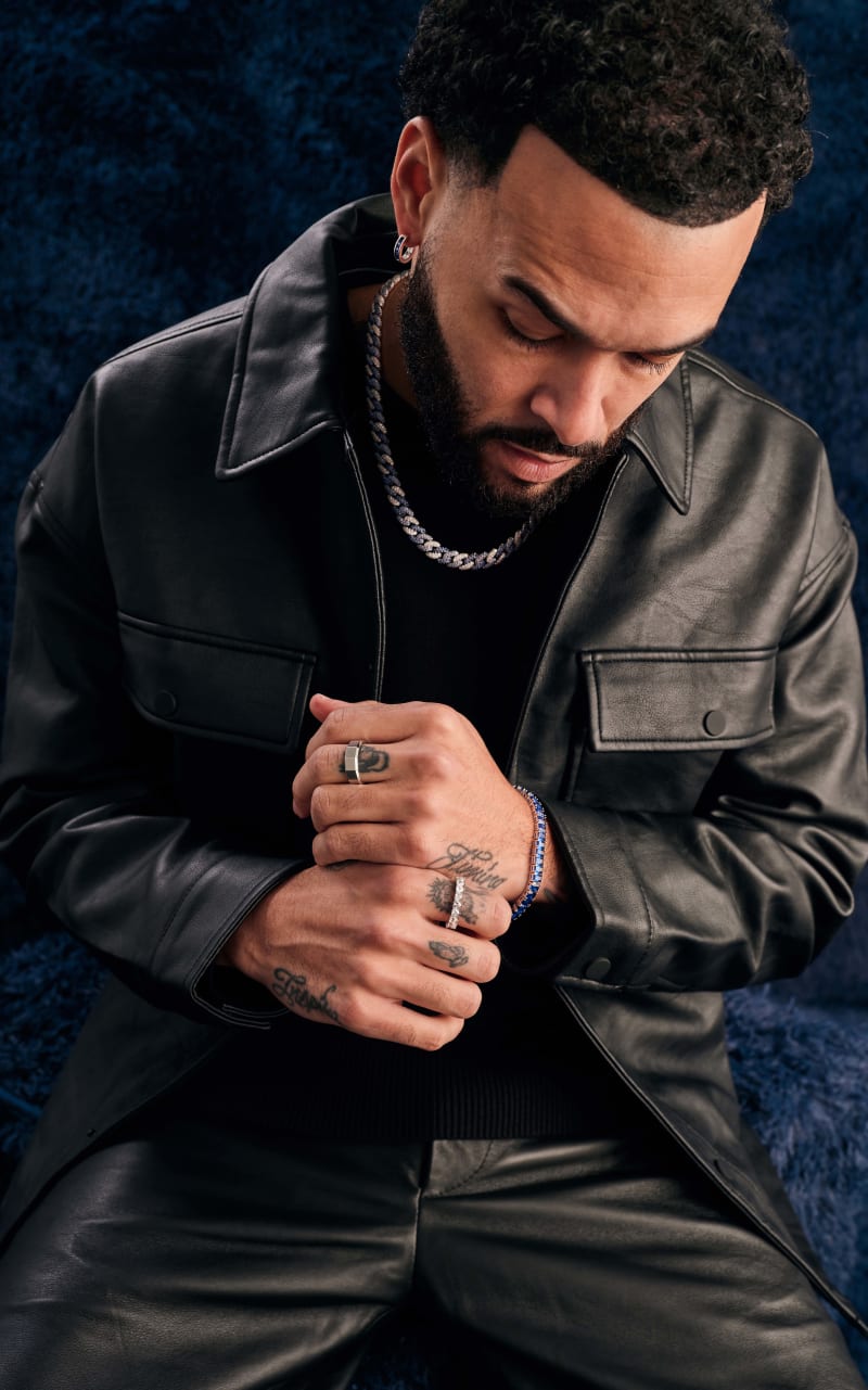 Don Benjamin wearing a black leather jacket and pants, and JAXXON jewelry pieces featuring the Blue Iced Out Cuban Link Chain.