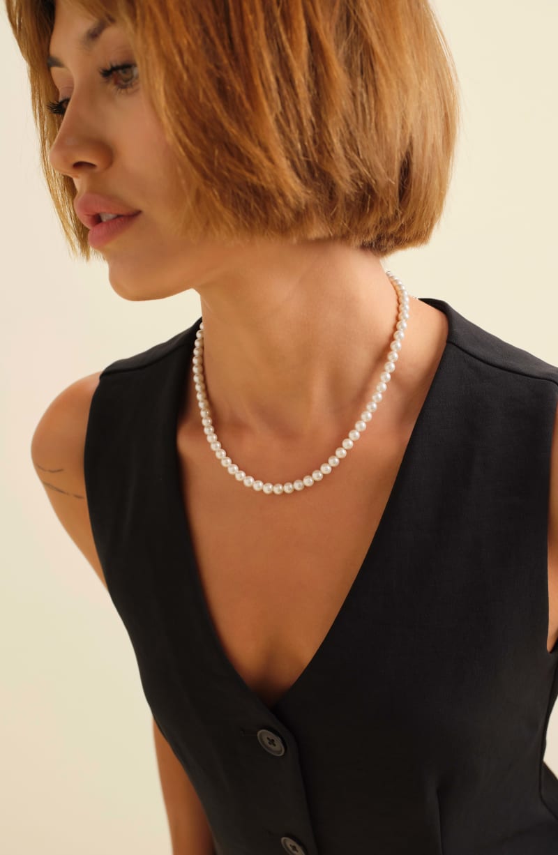Female model wearing a black sleeveless vest and the JAXXON 6mm Pearl Necklace.